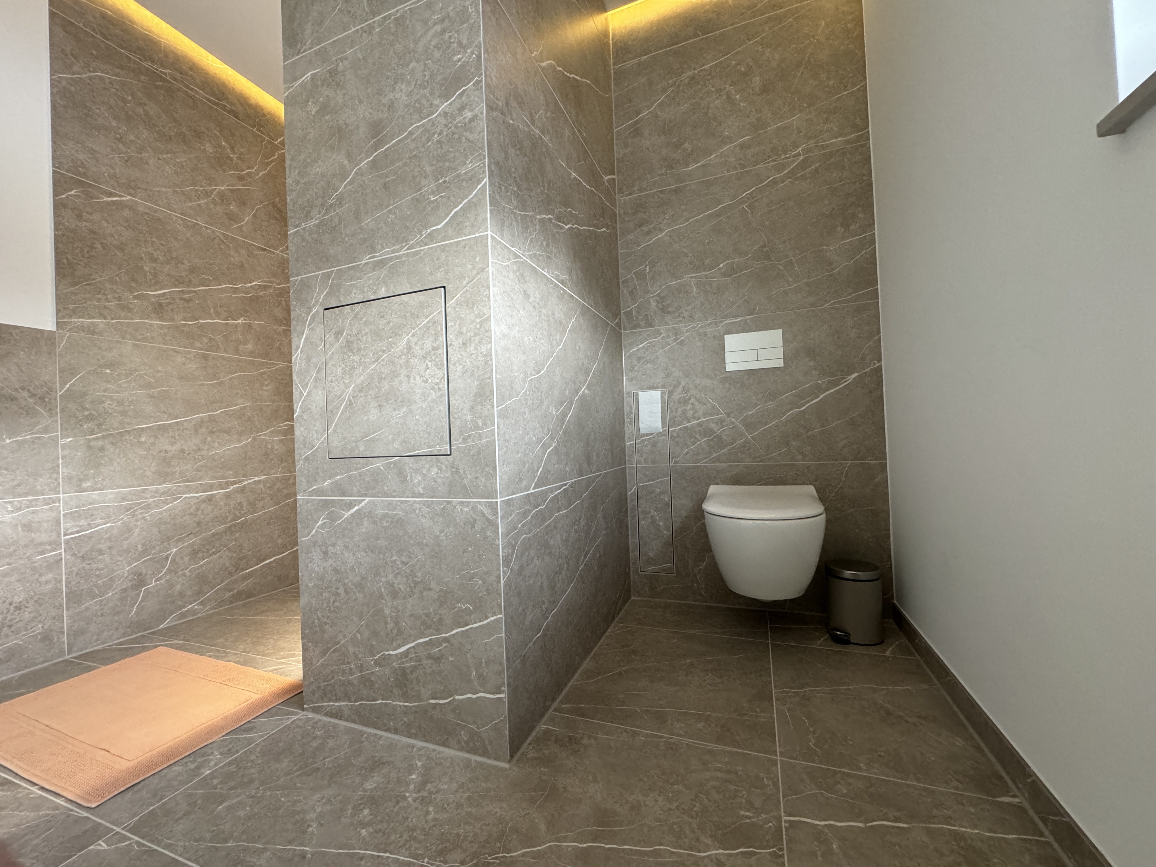 Geflieste Trennwand mit verstecktem Wäschedurchwurf zwischen Dusche und WC