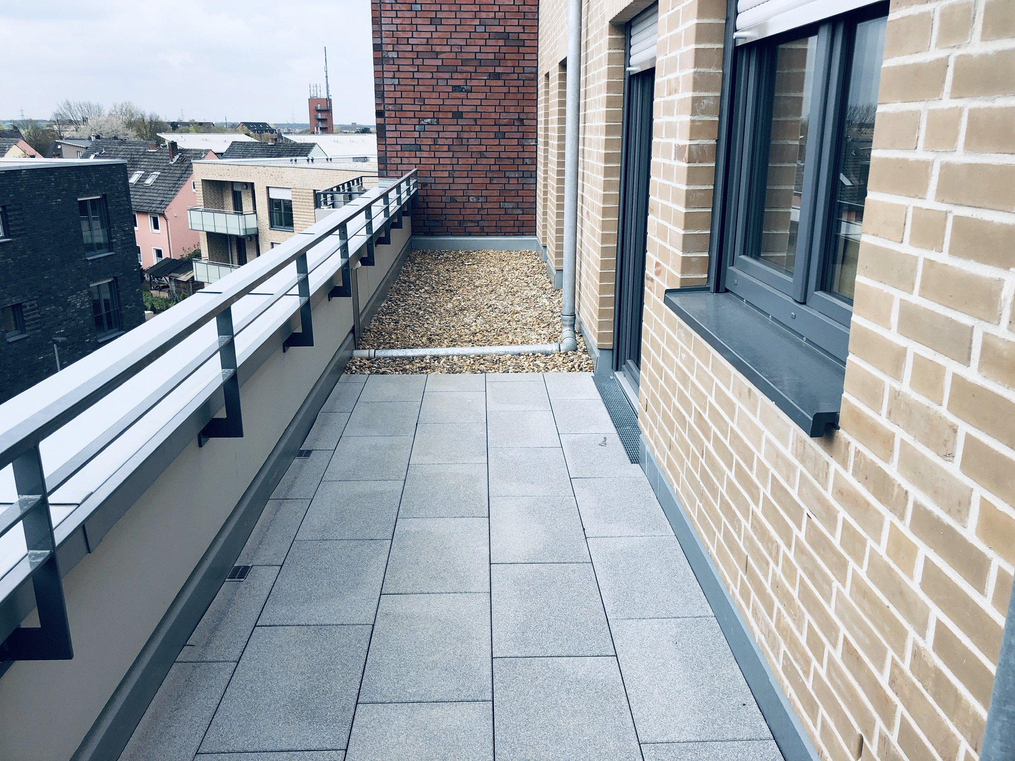 Langer Balkon mit grauen Balkonplatten an einer Klinkerfassade in Langenfeld