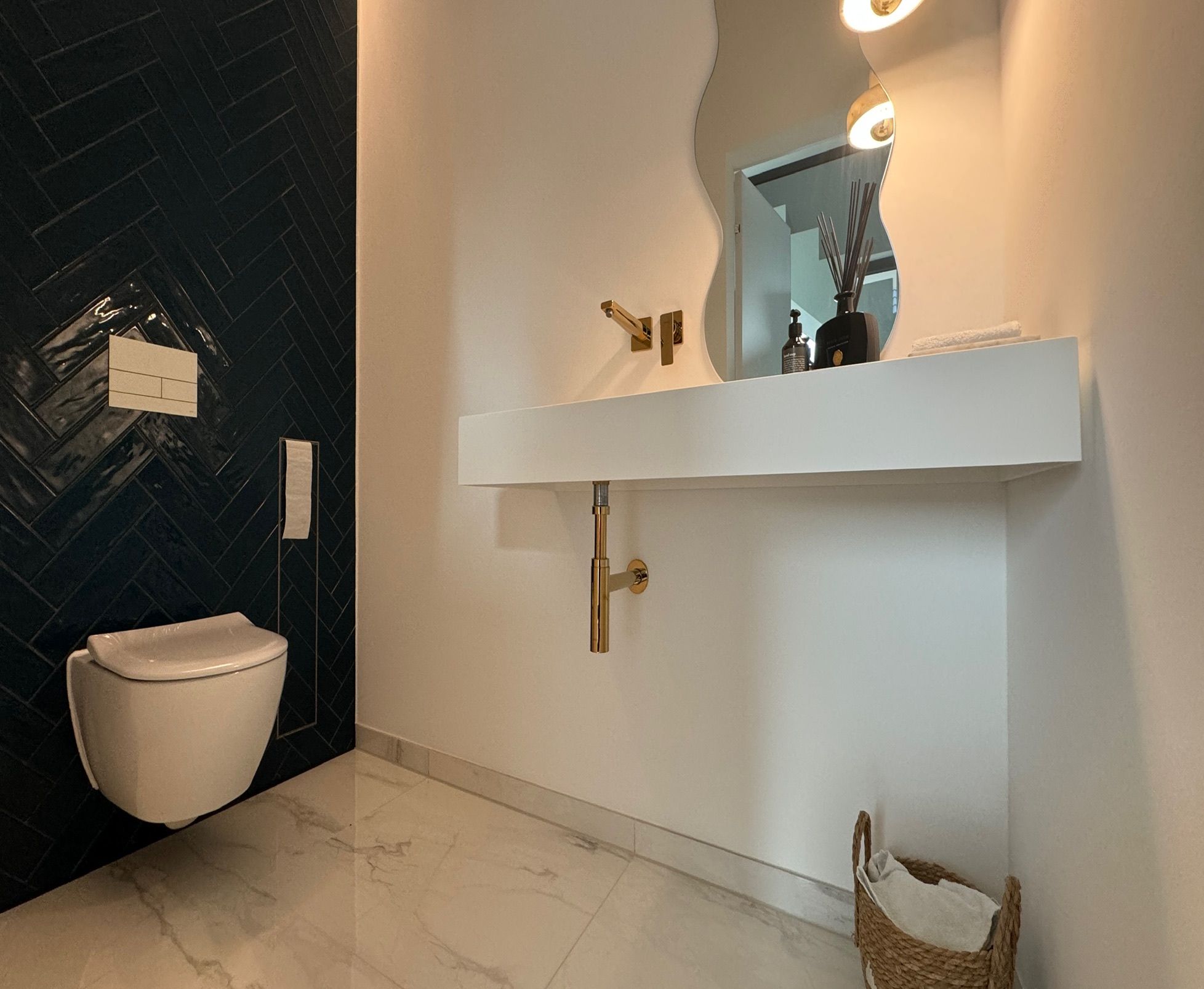 Gäste-WC in Kerpen mit petrolblauen Fischgrätfliesen, weißem Waschtisch und goldfarbenen Armaturen