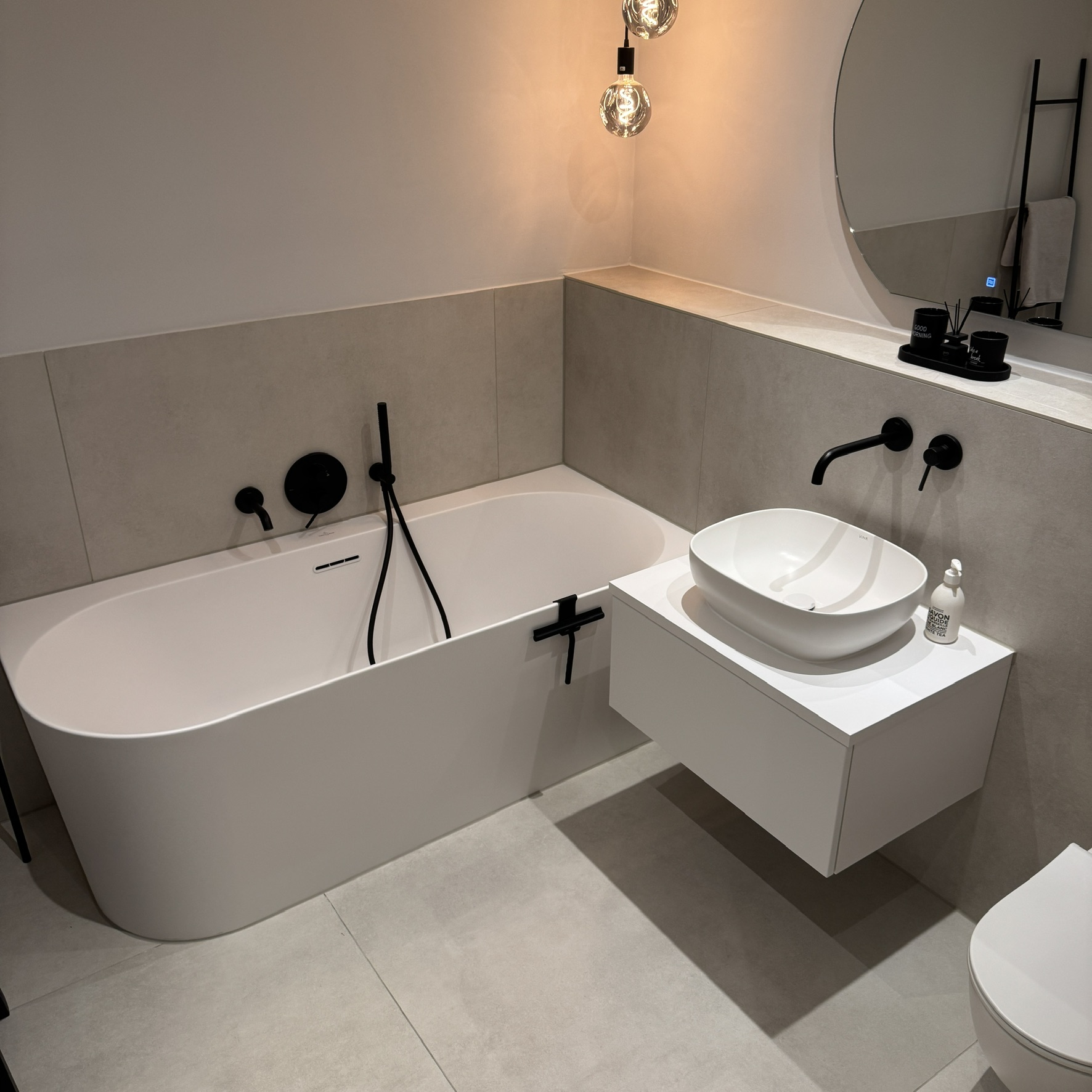 Weiße Badewanne und Aufsatzwaschbecken mit schwarzen Wandarmaturen im Neubauprojekt Düren