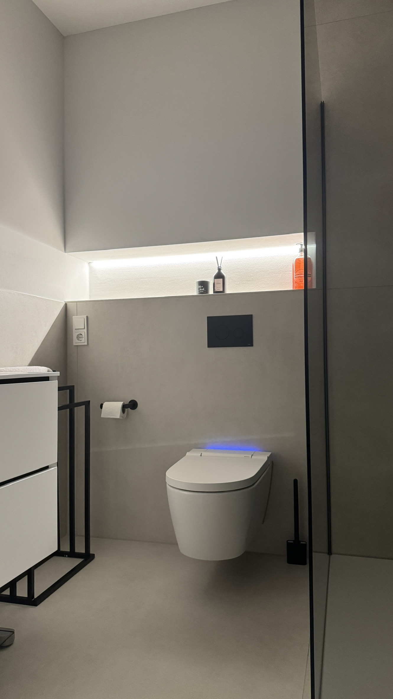 Wandhängendes WC unter beleuchteter Ablage neben der Glasabtrennung im Duschbad in Düren