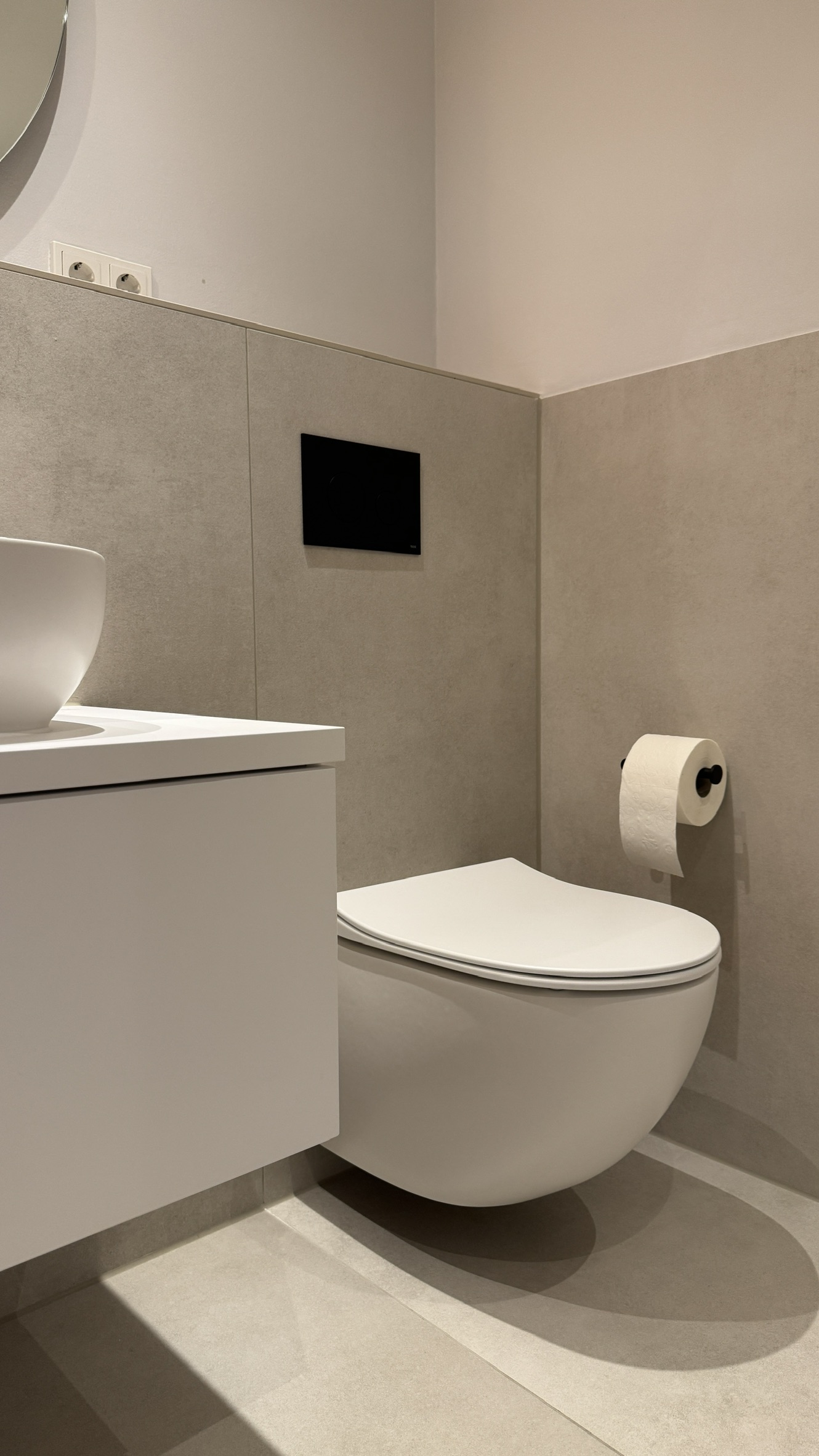 Wandhängendes WC und hellbeige Großformatplatten neben dem Waschtisch im Wannenbad in Düren
