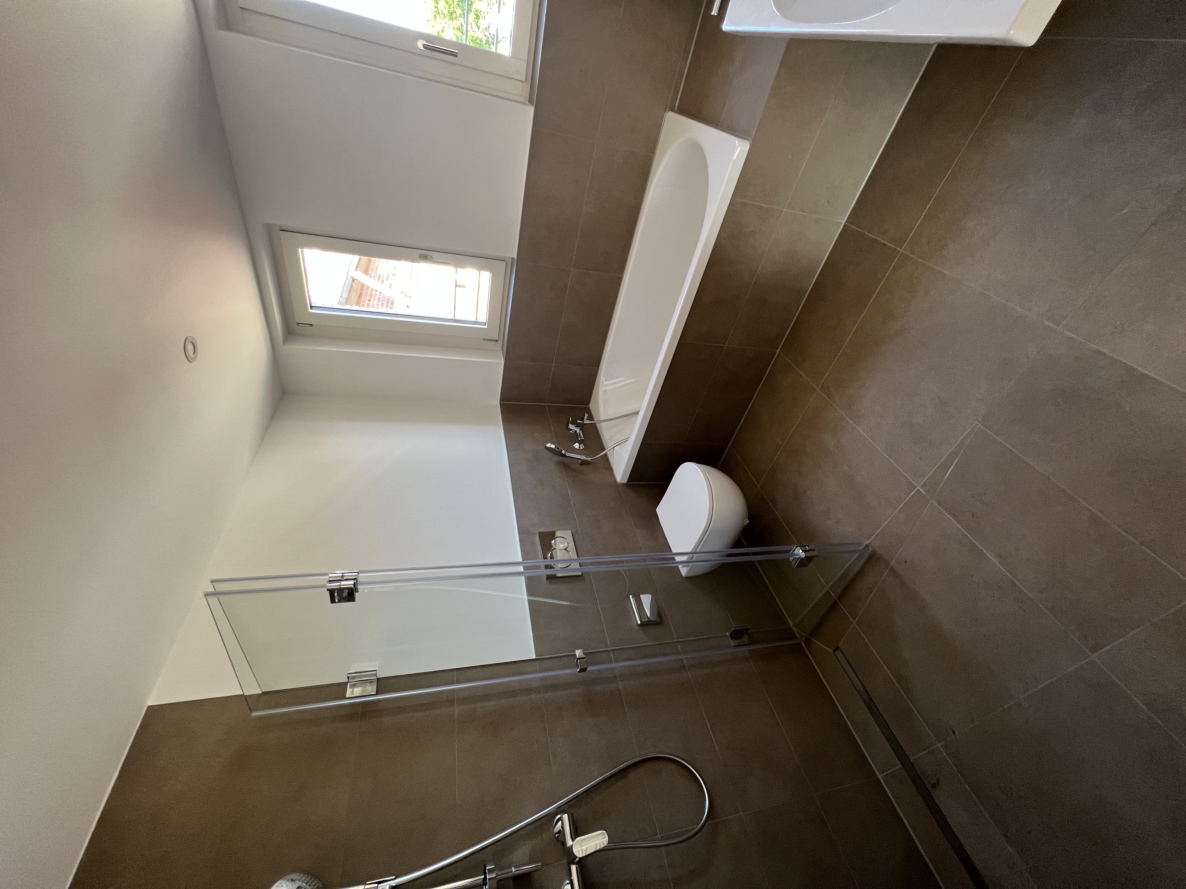 Badezimmer mit verkleideter Badewanne und bodenebener Dusche in Düren