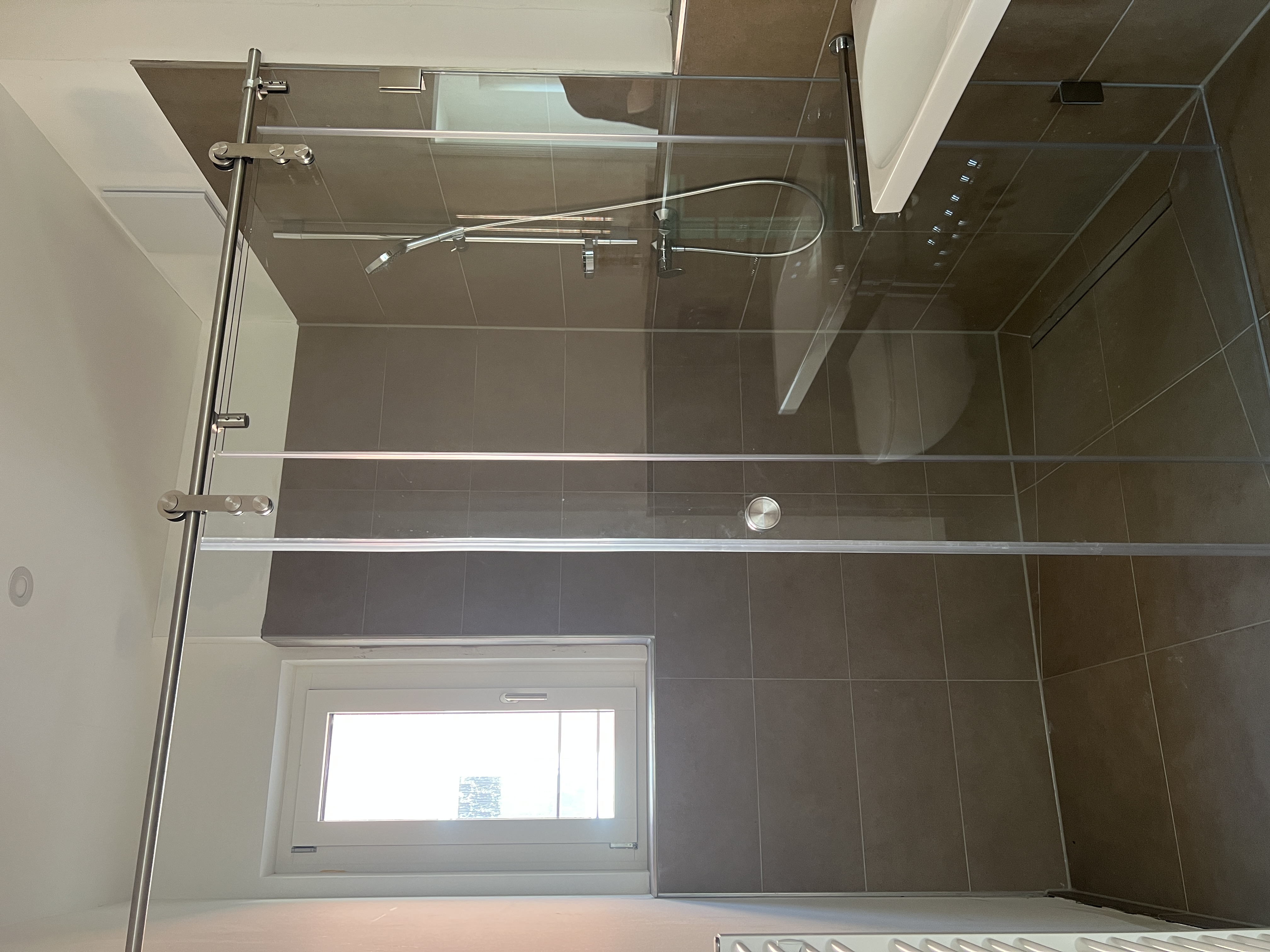 Bodenebene Dusche mit Glasabtrennung und braunen Fliesen in Düren