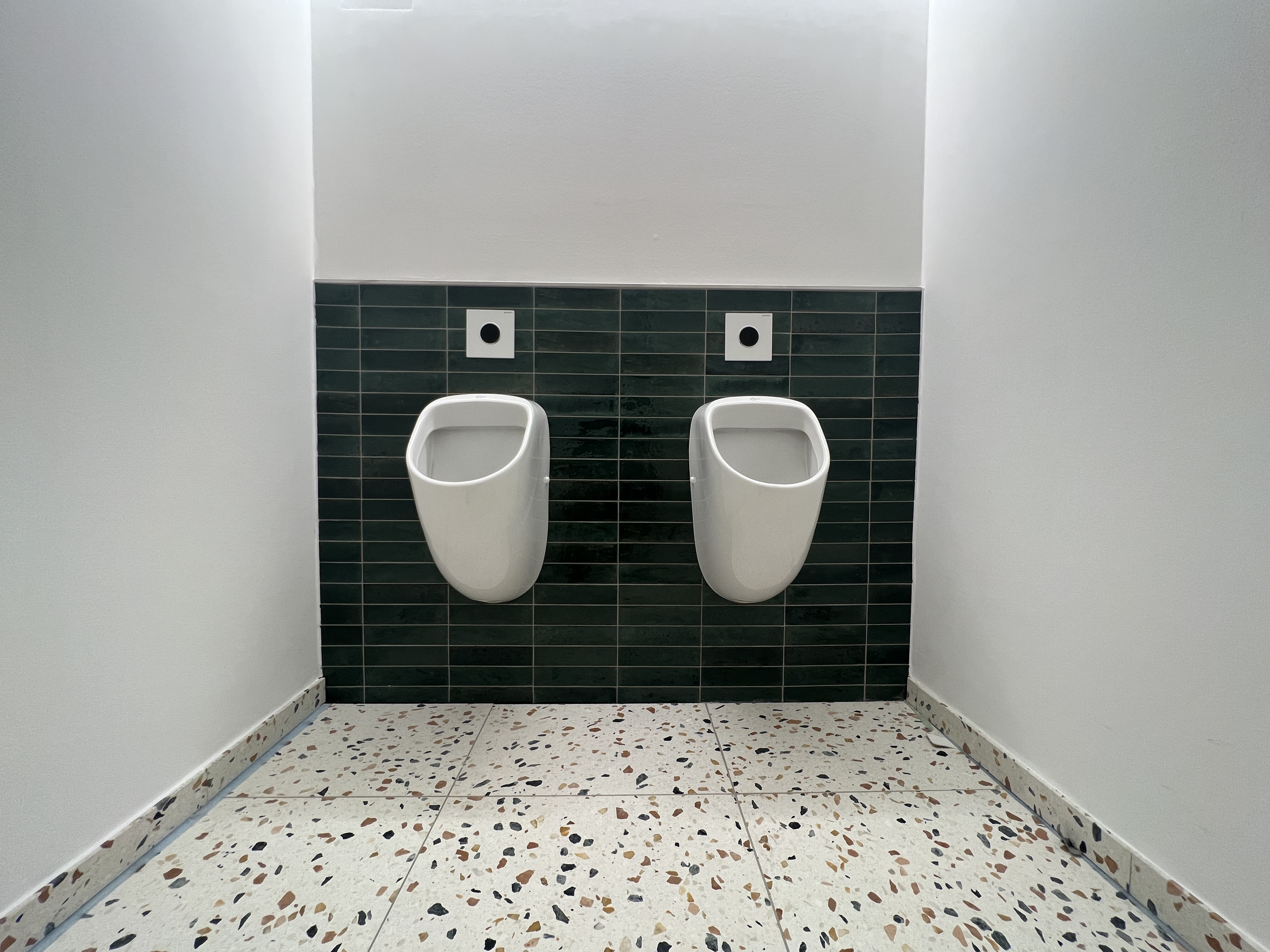 Zwei Urinale vor grünen Wandfliesen in der Gewerbeeinheit in Düren